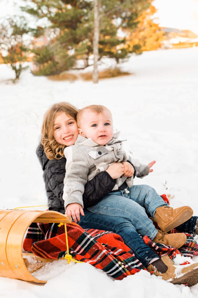 Siblings cuddling on a toboggan as one of the fun outdoor winter activities in Edmonton