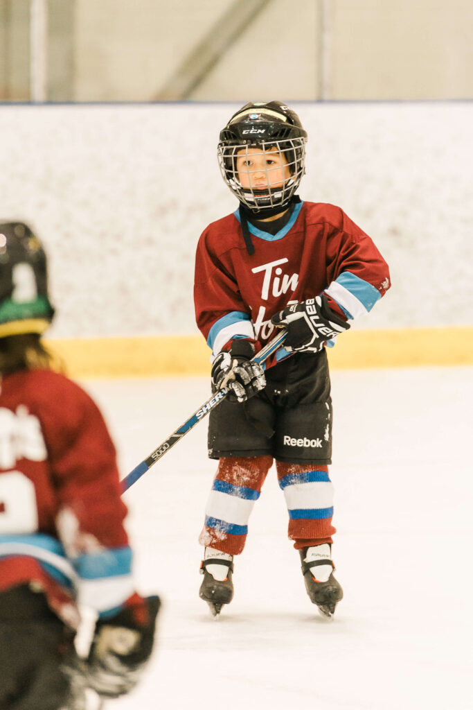 A kindergartener plays hockey during a tournament in an indoor hockey rink