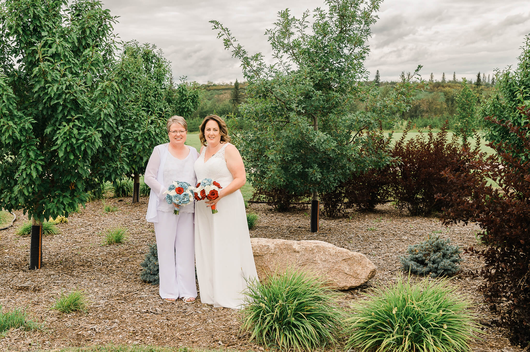 An LGBT wedding couple posing in front of West River's Edge in Fort Saskatchewan for wedding portraits with Cynthia Priest Photography