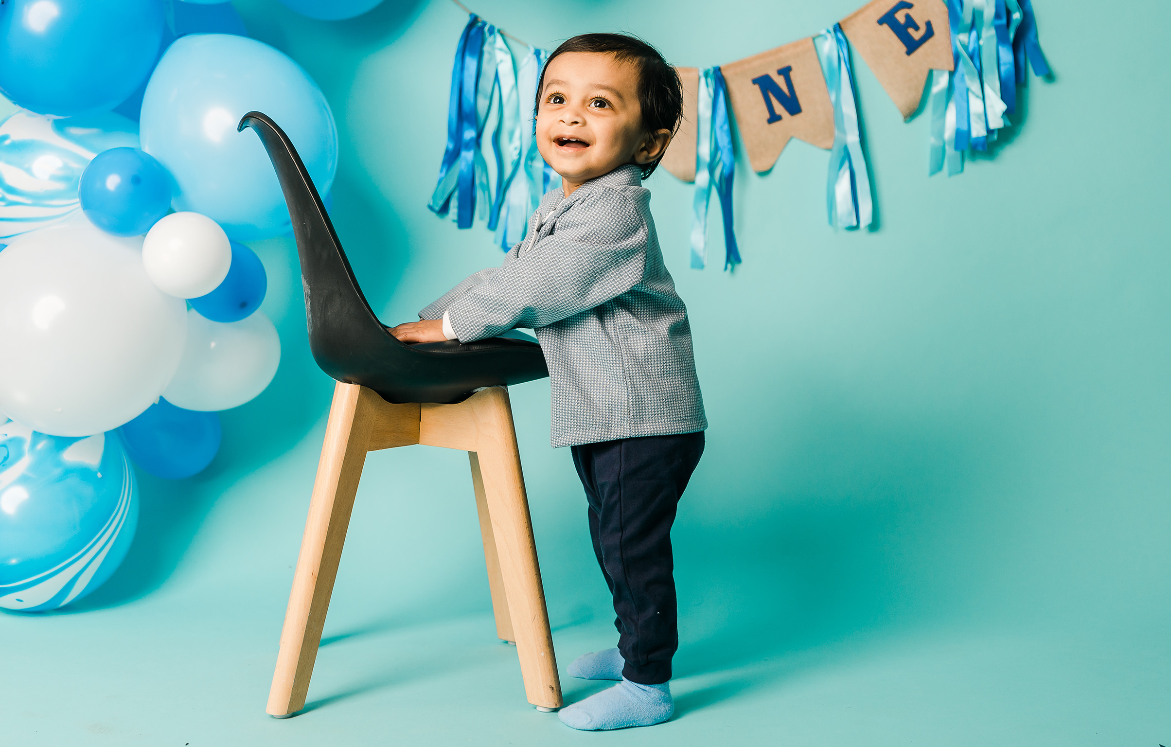 An Edmonton one year old having fun at a studio cake smash session that has balloons from one of Edmonton Toy Stores