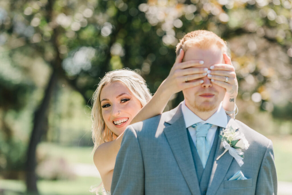 Bride holds groom's eyes with her hands during a first look