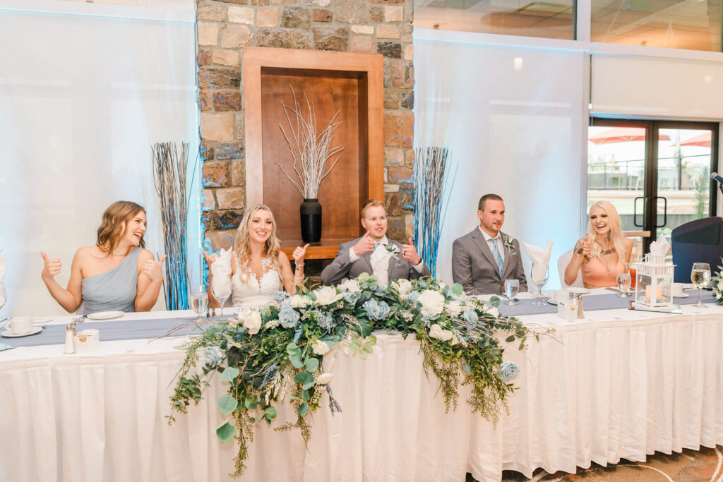 Wedding Couple and their bridesmaids & groomsman at The Derrick Golf and Winter Club at the white skirted head table with real flowers as the centrepiece