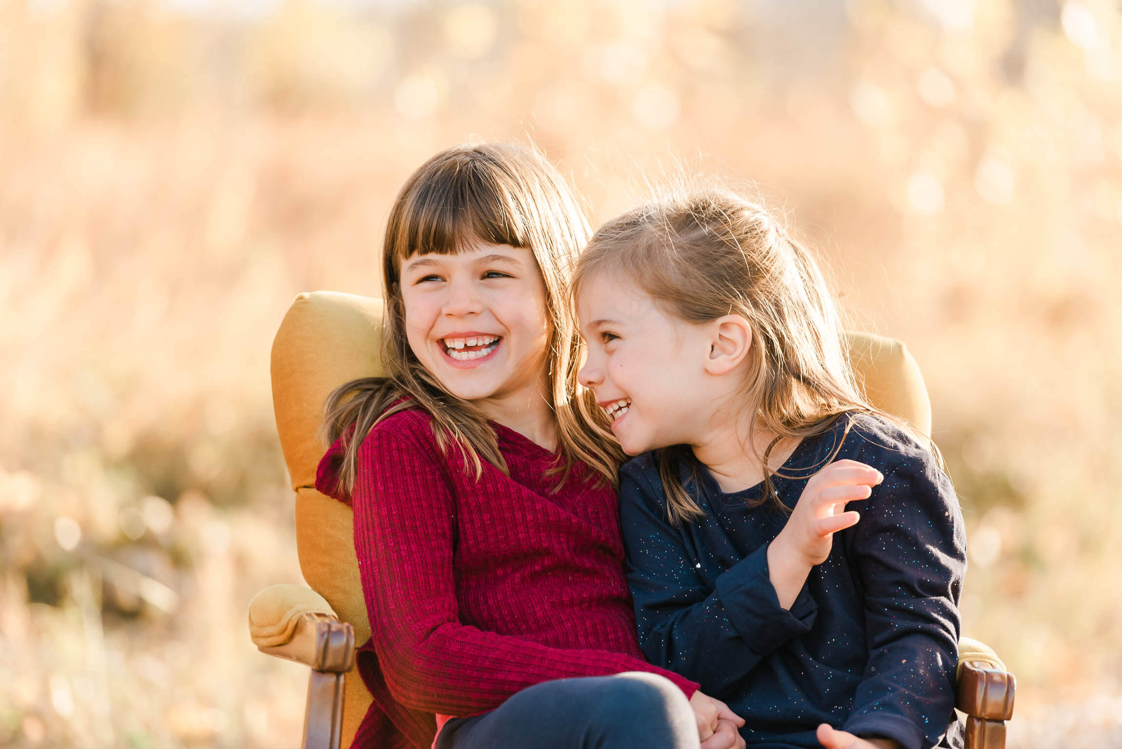 Two sisters in Edmonton gymnastics laughing during a photo session with Cynthia Priest Photography