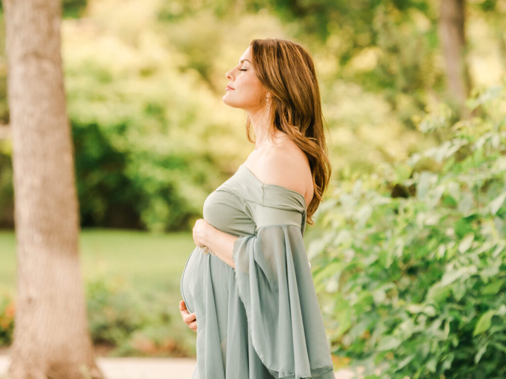 A pregnant Edmonton mom wearing an azure blue/green Mii Estilo maternty dress during a maternity session with Cynthia Priest Photography, taken at golden hour at the Edmonton legslature