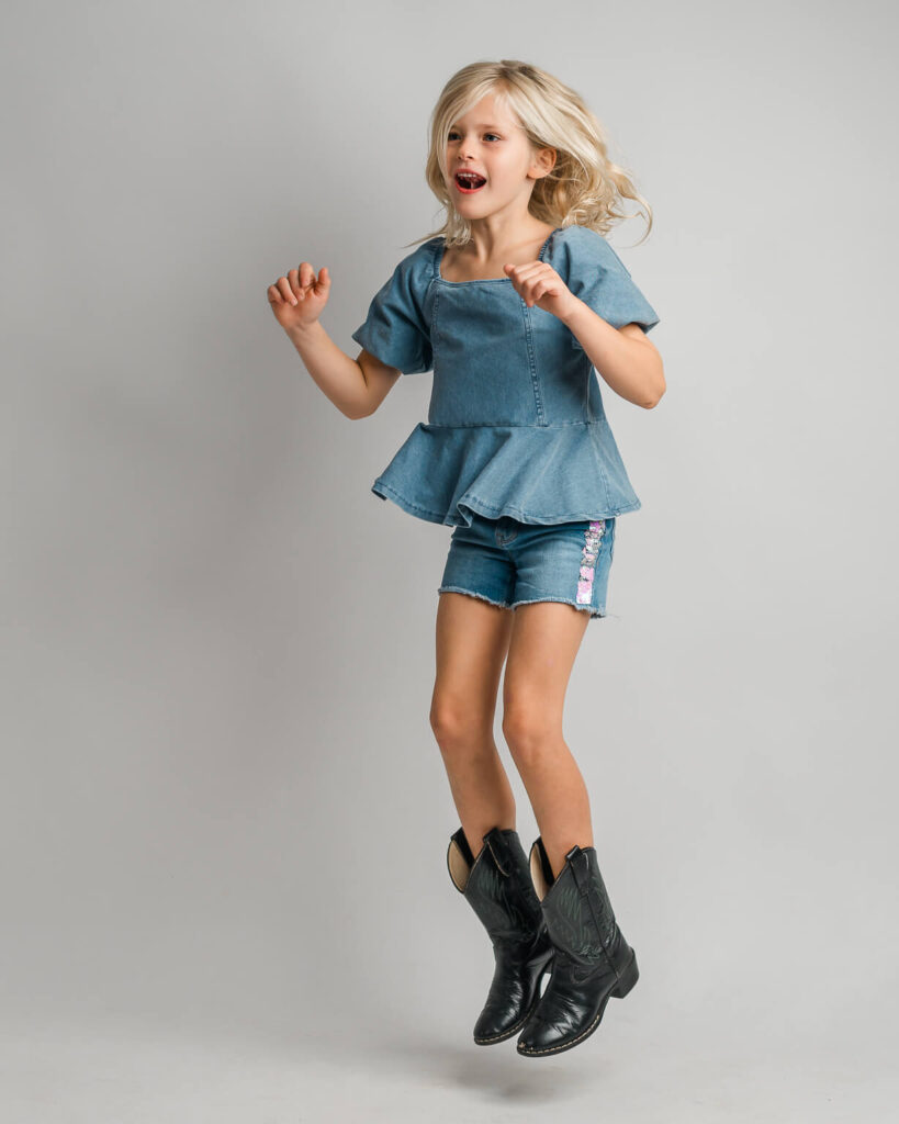 A white female kid jumping with playfulness