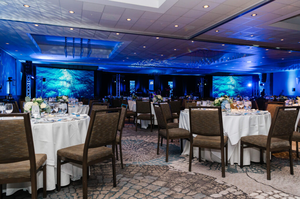 A low lit decorated ballroom with tables and chairs