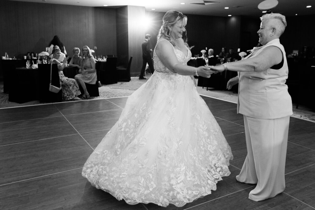 a woman in a wedding dress dancing with a woman in a wedding suit