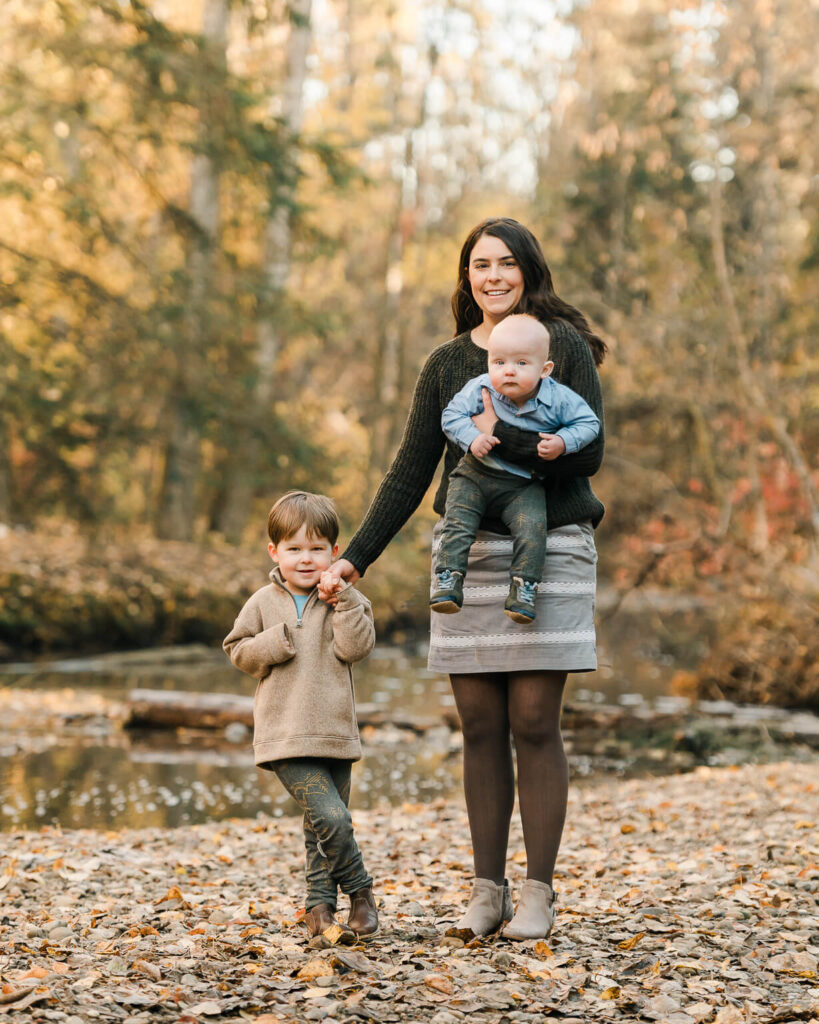 A mom holding a baby and a toddler's hand at Millcreek Ravine during autumn season