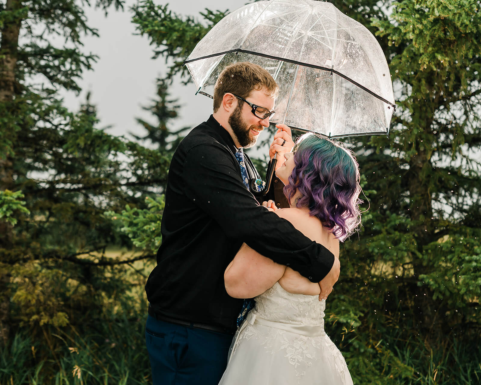 a groom and bride having a private moment, holding an umbrella in the rain before rejoining the reception with Soundfonix as DJ