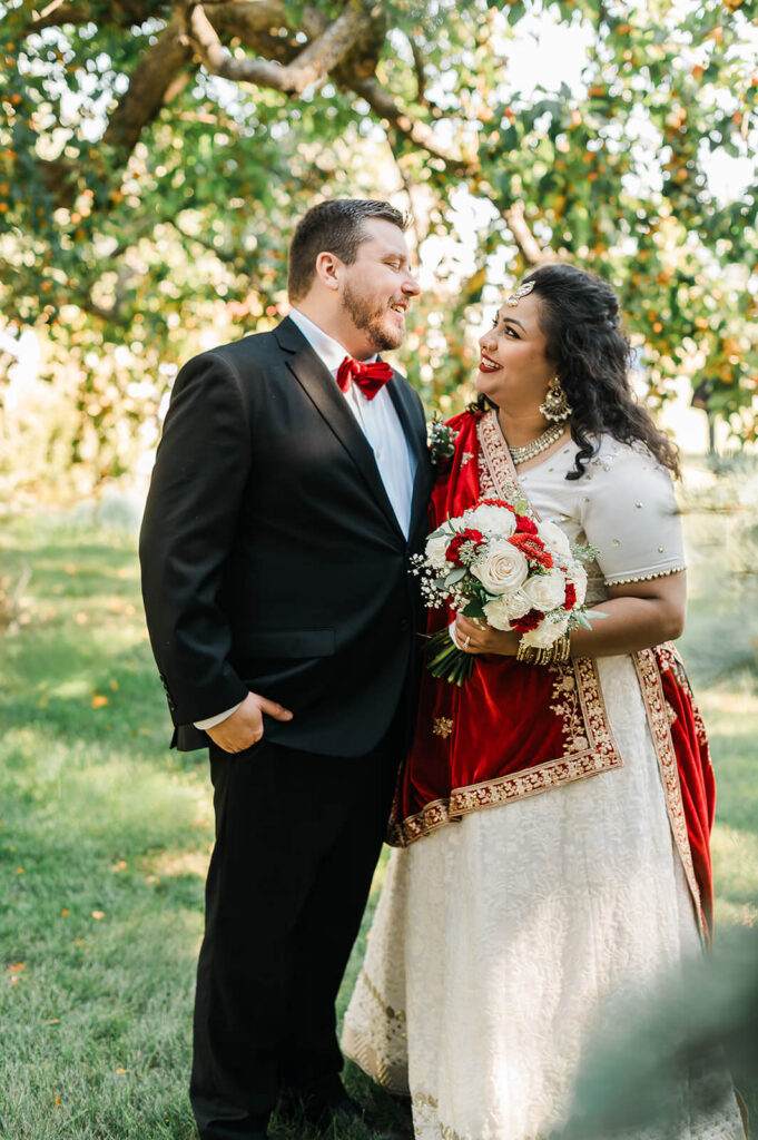A bride in a red sari during an outdoor Edmonton portrait session with a male groom