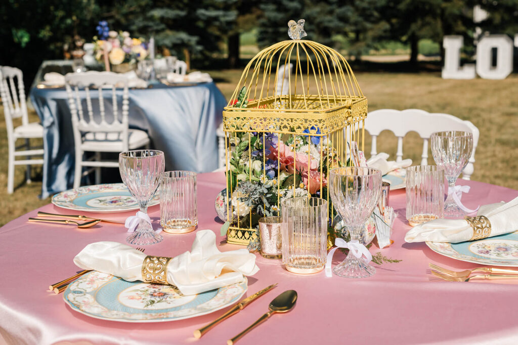 Gold birdcage floral centrepiece with vintage china and crystal glassware at a styled wedding reception designed by Oui Do Events