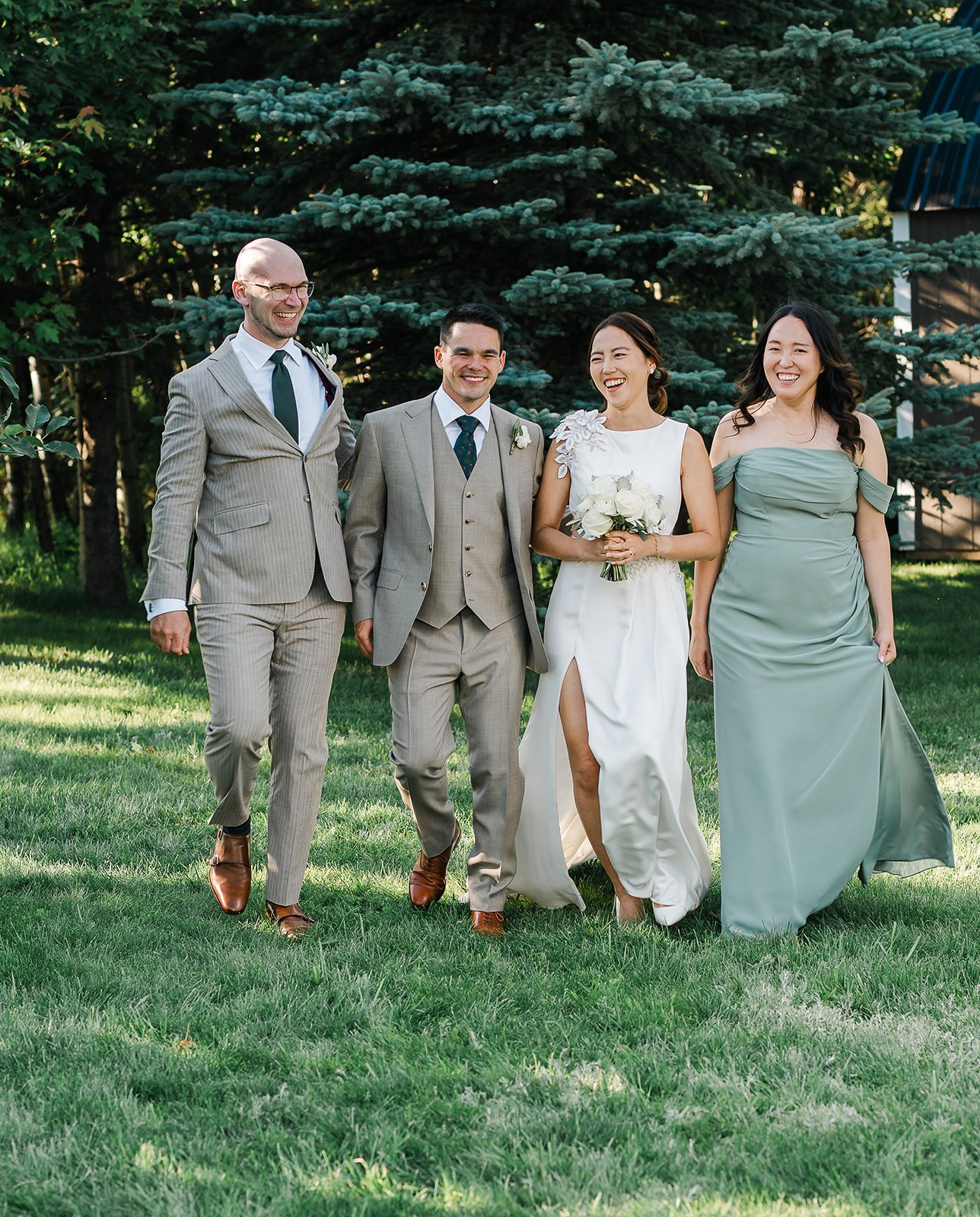 Wedding party in sage green and tan suits walking across the lawn in Sherwood Park